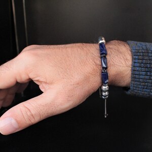 May include: A blue and silver beaded bracelet with a sliding knot closure.
