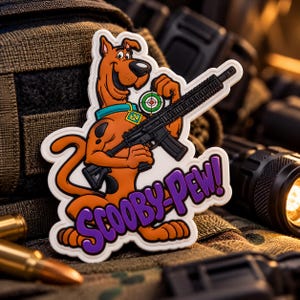 May include: A rubberized morale patch featuring a cartoon brown dog with black spots, a teal collar, and a yellow tag. The dog holds a black rifle and a green target icon. Below the dog, the purple text reads SCOOBY-PEW! in a bold font.