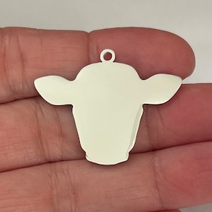 May include: White metal cow head charm with a loop at the top for hanging.