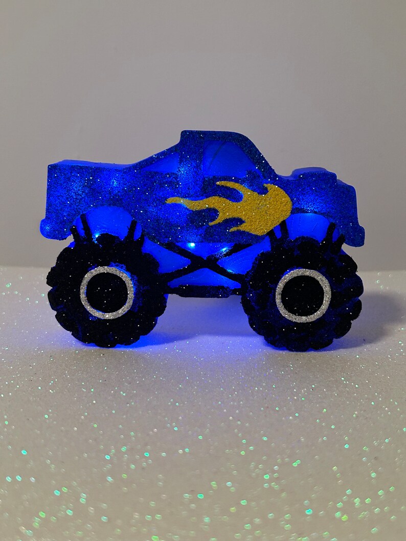 Pu&ograve; includere: Un topper per torta a forma di monster truck blu e oro con glitter. Il camion ha un design a fiamma sul lato ed &egrave; illuminato da luci blu.
