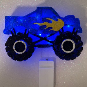 Pu&ograve; includere: Luce notturna a forma di monster truck blu glitterato con un design a fiamma dorata. La luce &egrave; alimentata a batteria e ha un interruttore bianco.