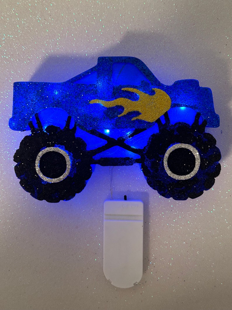 Pu&ograve; includere: Luce notturna a forma di monster truck blu glitterato con un design a fiamma dorata. La luce &egrave; alimentata a batteria e ha un interruttore bianco.