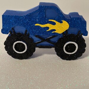 Pu&ograve; includere: Camion monster blu con pneumatici neri e un design a fiamma gialla. Il camion &egrave; fatto di schiuma e ricoperto di glitter.