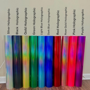 May include: A selection of holographic vinyl rolls in a range of colours: silver, black, gold, green, light blue, dark blue, red, rose gold, pink, and purple. Each roll is labelled with its colour name.