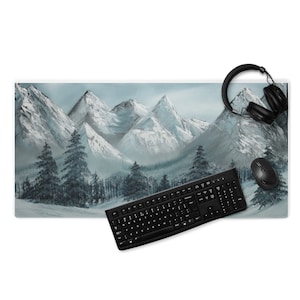 Puede incluir: Alfombrilla de escritorio rectangular con una pintura de paisaje de montañas nevadas en tonos grises y blancos. Un teclado, un ratón y unos auriculares negros están sobre la alfombrilla. La alfombrilla mide unos 79 cm de largo y 30 cm de ancho.