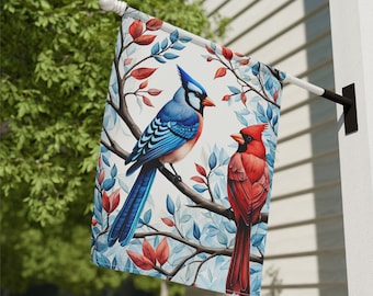 May include: A garden flag with a blue jay and a cardinal perched on branches with red and blue leaves. The flag is white with a watercolor-like design.