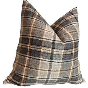 May include: A brown, gray, and white plaid throw pillow with a square shape.