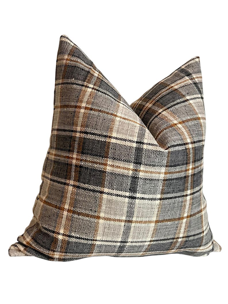 May include: A brown, gray, and white plaid throw pillow with a square shape.