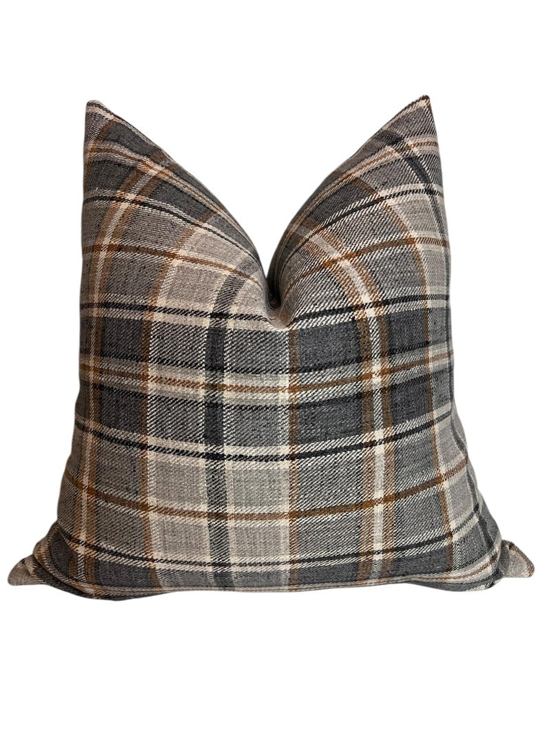 May include: A gray, brown, and white plaid throw pillow. The pillow is made of a soft, textured fabric.