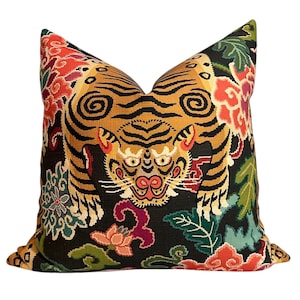 Puede incluir: Una almohada negra con un diseño de tigre colorido. El tigre está rodeado de flores y hojas en tonos rojos, rosas, verdes y azules.
