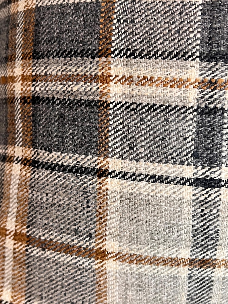 May include: Close-up of a brown, beige, and gray plaid fabric with a woven texture.