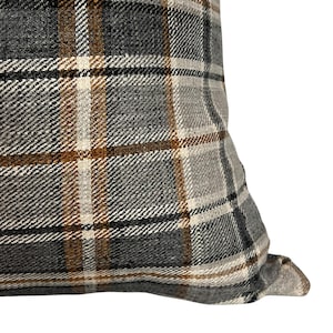 May include: Close-up of a gray, brown, and white plaid pillow cover. The fabric has a woven texture.