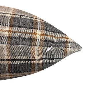 May include: A brown, gray, and white plaid throw pillow with a zipper closure.