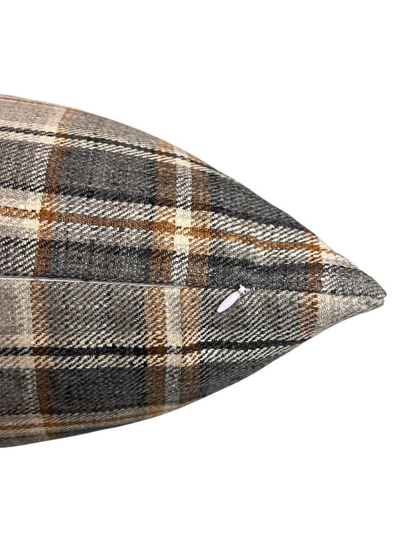 May include: A brown, gray, and white plaid throw pillow with a zipper closure.