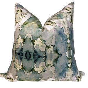 May include: A decorative throw pillow with a watercolor-style print featuring abstract shapes in shades of green, blue, and gray.