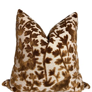 May include: A brown and cream throw pillow with a floral and animal design. The pillow is made of a soft, velvety fabric.