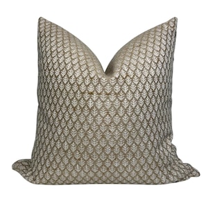 May include: A beige throw pillow with a white geometric pattern. The pillow is made of a soft, textured fabric.