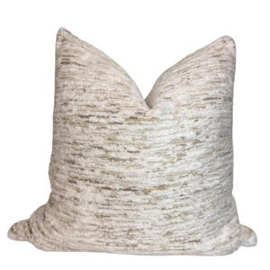 May include: A square decorative cushion in off-white with a textured surface. The cushion has horizontal stripes in beige and gold, creating a subtle pattern. The cushion appears plush and is designed for comfort.