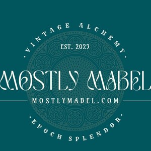 May include: A teal blue background with a white logo that says "Vintage Alchemy" and "Mostly Mabel" with a decorative circle design and the text "MostlyMabel.com" and "Epoch Splendor" around the circle. The text "Est. 2023" is inside the circle.