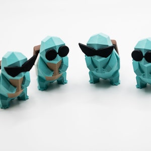 May include: Four teal blue 3D printed Squirtle figurines wearing black sunglasses. Each figurine has a brown shell on its back.
