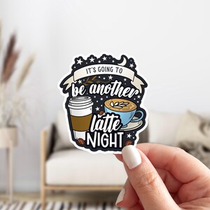May include: A sticker with a black background and white stars. It says "It's going to be another latte night." with a cup of coffee and a cup of latte.