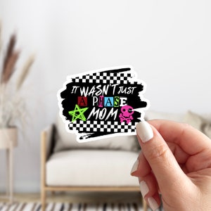 May include: Black and white checkered sticker with the text "It wasn't just a phase mom" in colorful letters. The sticker also features a star and a skull.