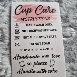 May include: A white card with "Cup Care Instructions" in black script and a pink watercolor wash. The card details care instructions: hand wash only, not dishwasher or microwave safe, and do not soak. It also says "Handmade with love, so please handle with care."