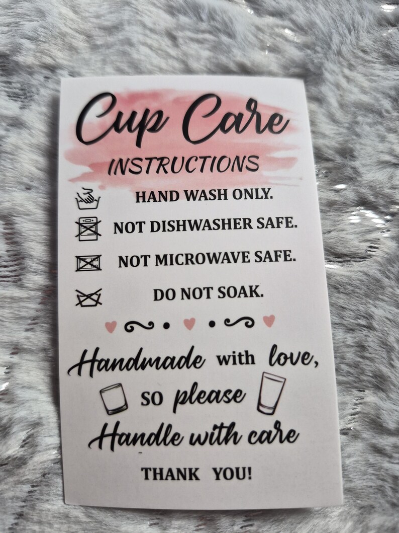 May include: A white card with "Cup Care Instructions" in black script and a pink watercolor wash. The card details care instructions: hand wash only, not dishwasher or microwave safe, and do not soak. It also says "Handmade with love, so please handle with care."