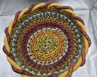 Cesta multicolor tejida a mano con espiral y borde retorcido.