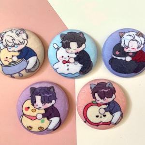 May include: Five round buttons featuring cartoon characters. Each button depicts a different character with a unique animal companion. The characters are dressed in various outfits and have different hair colours. The buttons are all white with a black outline.