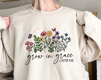 Peut inclure: Un sweat-shirt beige avec un motif floral et le texte "grow in grace 2 Peter 3:18".