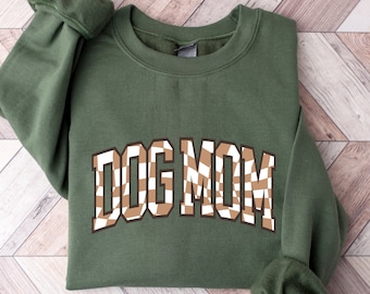 May include: A green sweatshirt with the text "DOG MOM" in brown and white checkered letters.