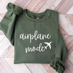 Puede incluir: Una sudadera verde con el texto "modo avi&oacute;n" y un avi&oacute;n blanco impreso en la parte delantera.
