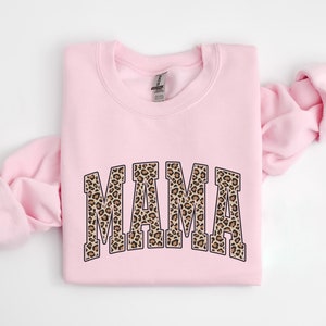 May include: Pink sweatshirt with a leopard print "MAMA" graphic.