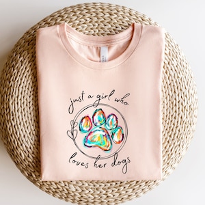 May include: A pink t-shirt with the text "just a girl who loves her dogs" and a colourful paw print graphic.