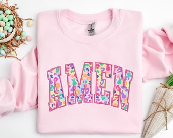 Puede incluir: Sudadera rosa con la palabra "AMEN" en letras grandes y coloridas con estampado de leopardo.