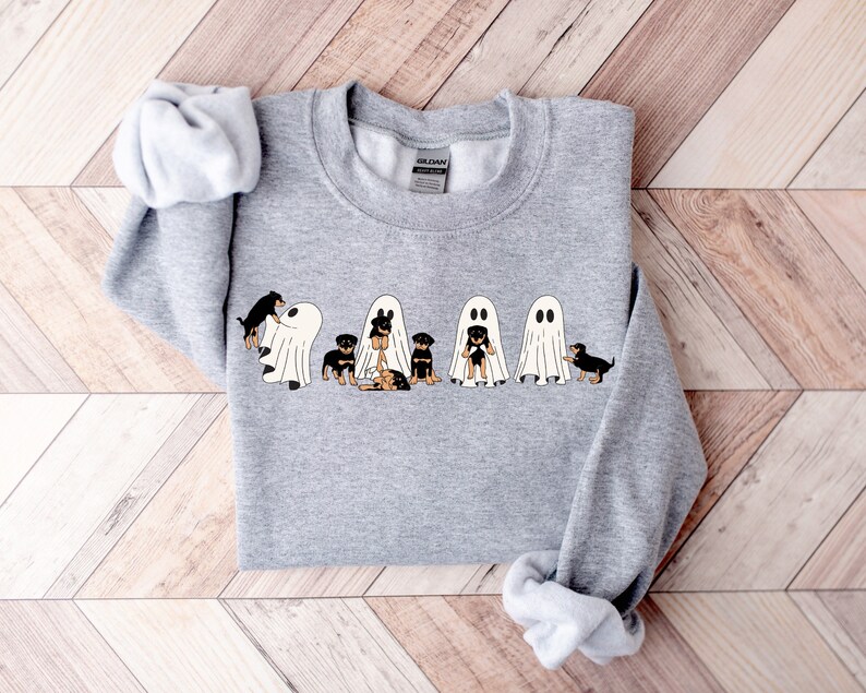 Op de afbeelding: Een grijs sweatshirt met een afbeelding van vijf zwarte en bruine honden die verkleed zijn als geesten voor Halloween.
