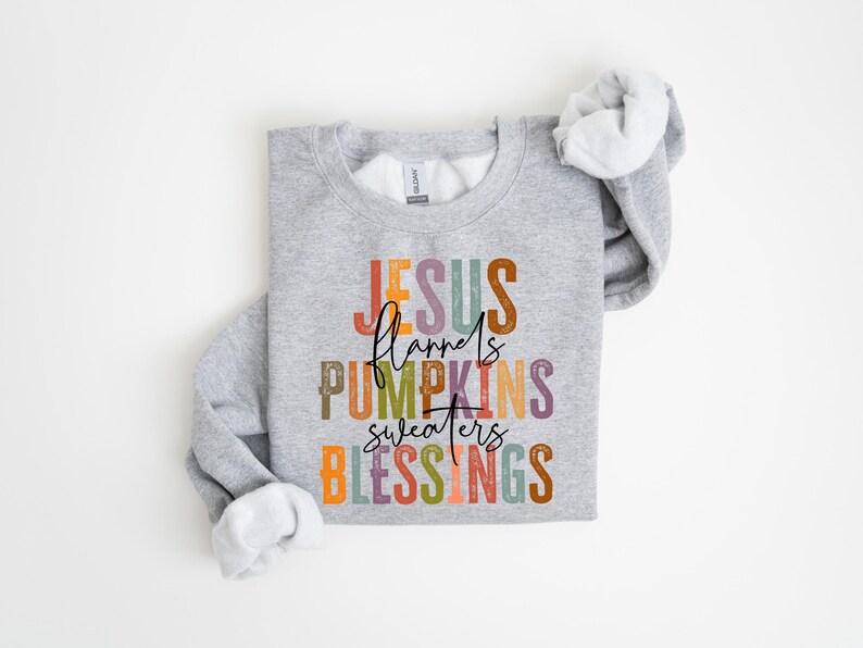 May include: A gray sweatshirt with the text "JESUS flannels PUMPKINS sweaters BLESSINGS" in colorful letters.