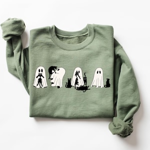 May include: A green sweatshirt featuring a white graphic of ghosts and black cats. The ghosts are wearing the cats as costumes.