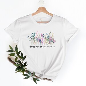 May include: White t-shirt with a floral design and the text "grow in grace 3 Peter 3:18"