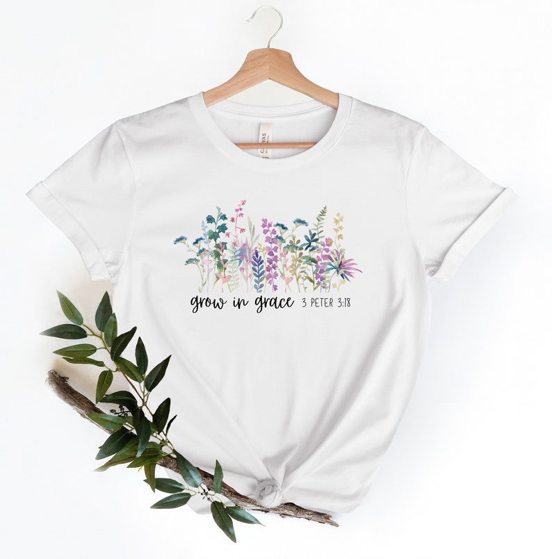 May include: White t-shirt with a floral design and the text "grow in grace 3 Peter 3:18"