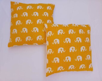 May include: Two yellow throw pillows with white elephant print. The pillows are made of cotton and have a quilted design.