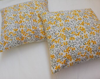 May include: Two white cotton pillow covers with a yellow floral pattern. The pattern features small yellow flowers with green stems and leaves on a white background.