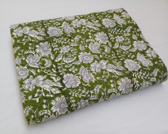 May include: Green fabric with a white floral pattern. The fabric is folded in half and has a textured surface.