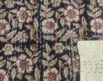 May include: A black and white kantha quilt with a floral pattern. The quilt is made of cotton and is hand-stitched. The quilt is reversible and has a plain white side.