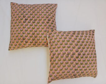 May include: Two peach-colored pillow covers with a floral pattern. The pattern is a repeating design of small pink flowers with green leaves.