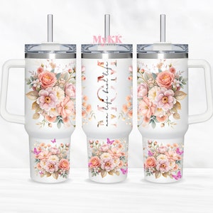Puede incluir: Taza de viaje de acero inoxidable blanca con un dise&ntilde;o floral y el texto "mom life best life". La taza tiene un asa y una tapa con una pajita.