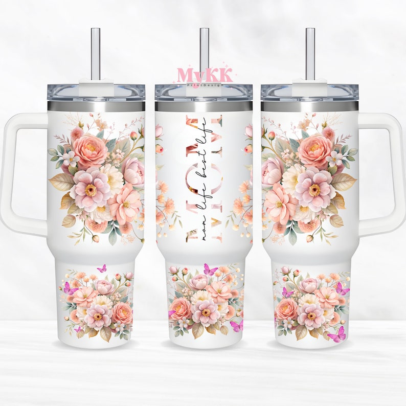 Puede incluir: Taza de viaje de acero inoxidable blanca con un dise&ntilde;o floral y el texto "mom life best life". La taza tiene un asa y una tapa con una pajita.