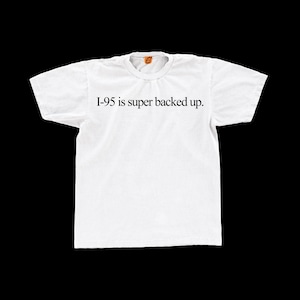 May include: White t-shirt with the text "I-95 is super backed up" in black. The shirt has a crew neck and short sleeves. The text is centered on the front of the shirt.