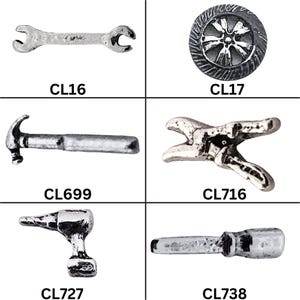 May include: A collection of silver-toned metal charms in the shape of tools. The charms include a wrench, a tire, a hammer, pliers, a drill, and a screwdriver. Each charm has a unique design and is labeled with a code.